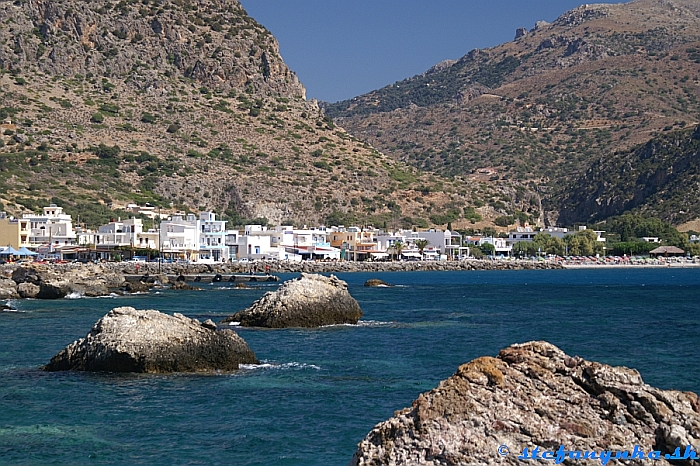 Stredisko Paleochora (vstup od prístavu) na juhozápade Kréty. Cesta z Chanie vedie cez roklinu na obrázku. Vpravo sa nachádza kamienková pláž a camping
