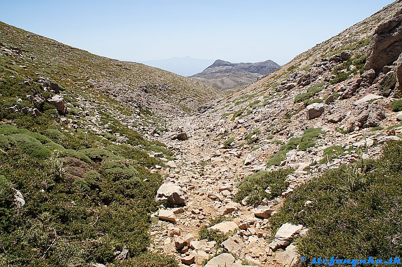 Zostup z Psiloritisu. Údolie vedie k rázcestiu Akolita. Dvojvrchol je Mavri a vľavo od neho v opare v pozadí je Kofinas