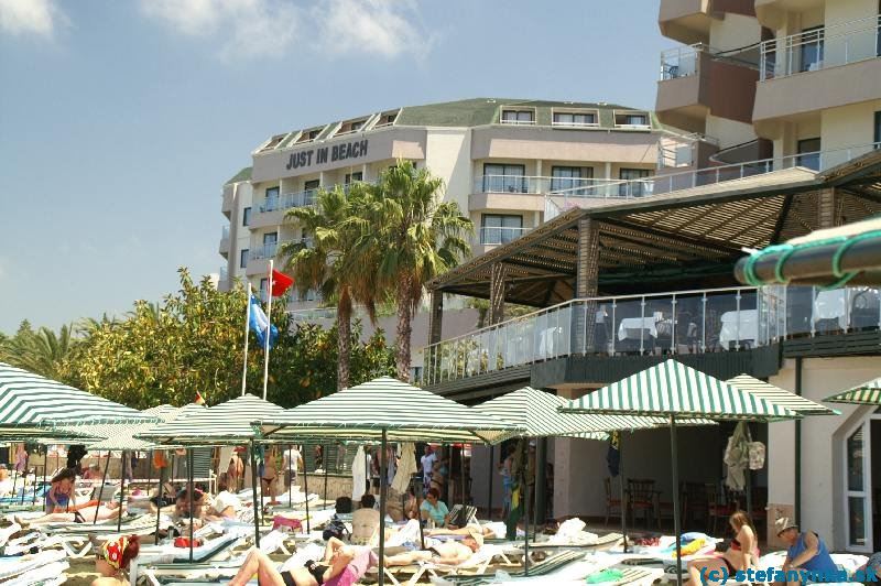 Pohľad na hotel Aska Just in Beach od pláže. Úplne vpravo je blok A s terasou reštaurácie, vzadu za palmami blok B.