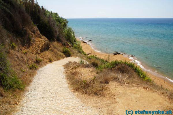 Južná časť pláže v Agios Georgios south, za tavernou Malibu. Tu končila piesková pláž. Vpredu začínala asi kilometrová časť po nepríjemných kameňoch